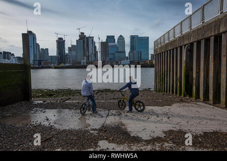 Zwei Männer auf BMX Fahrräder in Greenwich Halbinsel mit Blick auf Canary Wharf Financial District über die Themse, London, England, Vereinigtes Königreich Stockfoto