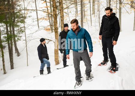 Eine Gruppe von Freunden (alle Ende 30) Schneeschuhwandern durch den Wald im Winter. Mont Tremblant, Quebec, Kanada Stockfoto