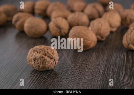 Walnüsse closeup gegen dunkle Holz Tisch Hintergrund. Walnuss vor. Vintage coolen Look anzeigen Stockfoto