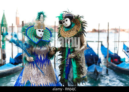 Venezianische Masken Modell aus der Karneval von Venedig 2019 mit Gondeln im Hintergrund Stockfoto