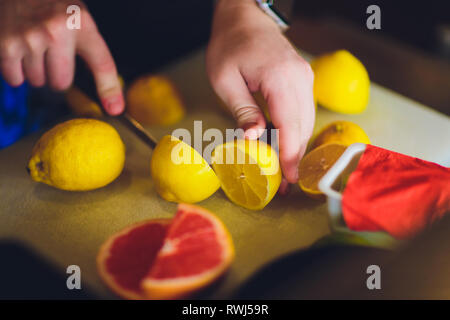 Frau slicing Zitrone auf einem Kunststoff Schneidebrett in der Küche Stockfoto