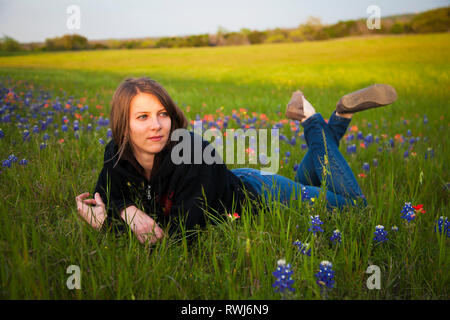 Eine junge Frau, die Verlegung in ein Feld von bluebonnet Wildblumen, Waco, Texas, Vereinigte Staaten von Amerika Stockfoto