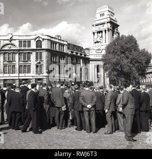 1950er Jahre, der Mittagspause und eine Masse der Stadt Männer in Anzügen sammeln zu beobachten und zu einem Mann, ein Generalvikar zu hören, die eine öffentliche Rede in der open-air in Southwark, London, durch die Büros von Hays Wharf Limited, England, UK. Stockfoto