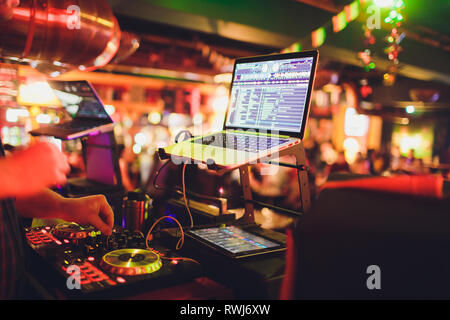 Hände von DJ Mix Tracks auf digitale Drehscheibe und Software auf Laptop mit Professional Mixing Software. Disc Jockey spielen Musik zeigen Stockfoto