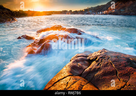 Sonnenuntergang an der St. John's Hafen, Wellen, die über Felsen im Vordergrund, St. John's, Neufundland und Labrador Stockfoto