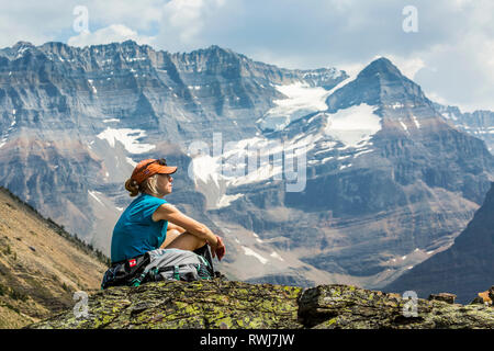 Weibliche Wanderer sitzen auf einem Felsen mit Blick auf die Berge Vista im Hintergrund; British Columbia, Kanada Stockfoto