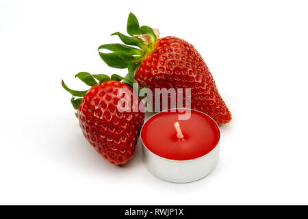 Zwei ganze Erdbeere Früchte und Kerze auf weißem Hintergrund Stockfoto