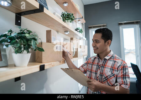 Asiatische Arbeiter Blick in die Boxen auf einem Holzregal im Büro Zimmer und prüfen Stockfoto