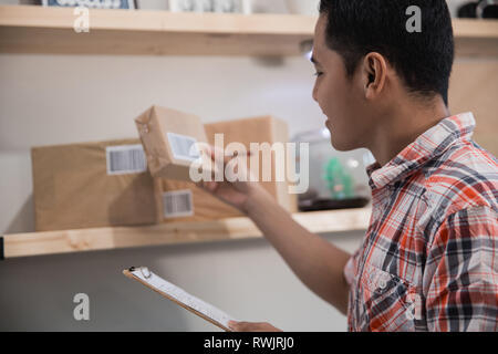 Nahaufnahme der asiatischen jungen Mann sehen Sie sich die Box in einem hölzernen Regalen Stockfoto