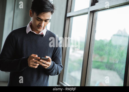 Bild des asiatischen jungen Mann mit Smartphone Stockfoto