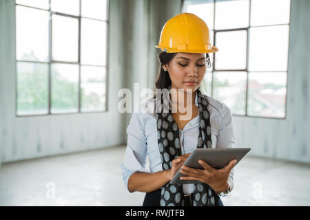 Frau Ingenieur tragen, hardhat halten eine digitale Tablet Stockfoto