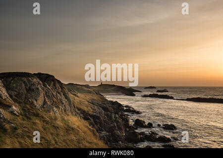 An der Küste Blick auf einen Winter Sonnenuntergang, den Blick von der Halbinsel im Abend Licht, am Llanddwyn Island, Anglesey, Nordwales. Stockfoto