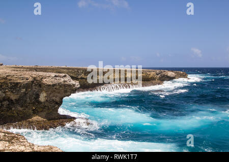 Wild und hohe Wellen am rauen vulkanischen Felsen der Ostküste der tropischen Insel Bonaire brechen Stockfoto