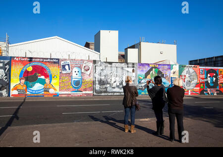 Republikanische Wandmalereien, bekannt als die „Internationale Mauer“, die Szenen aus der ganzen Welt, insbesondere aus dem Nahen Osten, auf der Falls Road in Wes... Stockfoto