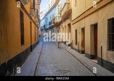 Ein älterer Mann Spaziergänge durch die engen Straße zwischen Wohngebäuden; Cadiz, Andalusien, Spanien Stockfoto