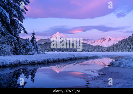 Alpenglow-Farben die schneebedeckten Berge der Küstenkette, der Mendenhall-Gletscher und die Mendenhall-Türme spiegeln sich im offenen Wasser entlang des Randes... Stockfoto