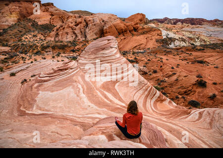 Frau, die in der Meditation pose sitzen am Feuer Wave Sandstein Felsformationen im Valley of Fire State Park, Nevada. Stockfoto