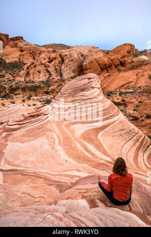 Frau, die in der Meditation pose sitzen am Feuer Wave Sandstein Felsformationen im Valley of Fire State Park, Nevada. Stockfoto