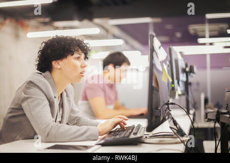 Junge weibliche Software Entwickler, die mit Desktop Computer beim Schreiben von Programmcode auf modernen, kreativen Start Büro Stockfoto