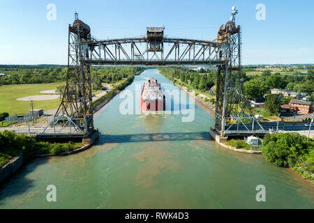 Luftaufnahme von großen laker Schiff Navigation unter einem Metall lift Bridge in einem Kanal mit blauen Himmel; Thorold, Ontario, Kanada Stockfoto