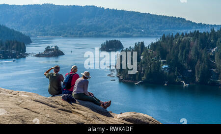 Wanderer sitzen im Steinbruch Felsen auf dem Baden-Powell Trail mit Blick auf die Küstenlinie, Deep Cove, North Vancouver, Vancouver, British Columbia, Kanada Stockfoto