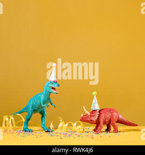 Zwei Dinosaurier mit Geburtstag hüte Feiern auf einem gelben Hintergrund. Stockfoto