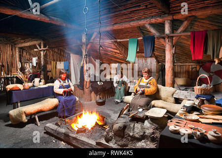 Reenactors in historischen Kostümen, die traditionellen Aufgaben innerhalb eines neu Wikinger langhaus an norstead Viking Village und Port des Handels, L'Anse aux Meadows, Neufundland, Kanada Stockfoto