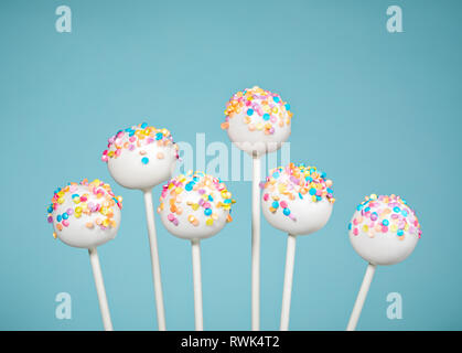 Vanille Kuchen Pops mit bunten Streuseln über einen blauen Hintergrund. Stockfoto