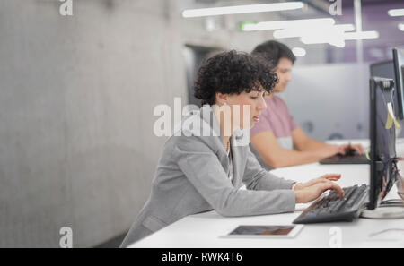 Junge weibliche Software Entwickler, die mit Desktop Computer beim Schreiben von Programmcode auf modernen, kreativen Start Büro Stockfoto