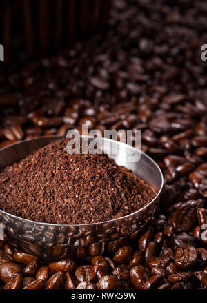 - Nahaufnahme Blick auf eine Schale mit frisch gemahlenem Kaffee auf einem Bett aus gerösteten Ganzen, ungemahlenen Kaffeebohnen Stockfoto