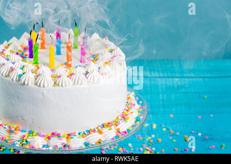 Weiß Buttercream Vereisung Geburtstagskuchen mit Kerzen heraus über blauen Hintergrund durchgebrannt Stockfoto