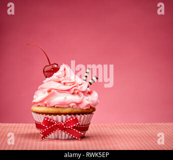 Cupcake mit Rosa buttercream Vereisung und eine Kirsche auf. Stockfoto