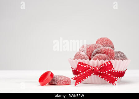 Sweet red cherry Bonbons in einem Pappbecher mit einem roten Bogen Stockfoto