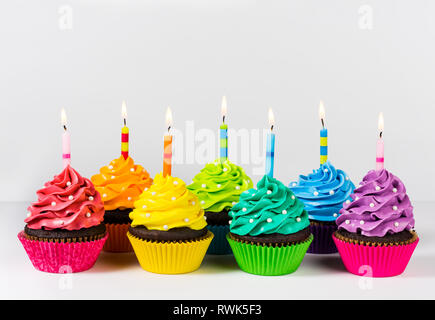 Reihen von bunten cup cakes mit Geburtstag Kerzen dekoriert und Streuseln. Stockfoto