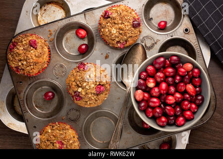 Frisch gebackene cranberry Muffins mit Haferflocken krümeln Richtfest in einem rustikalen Muffin tin. Stockfoto