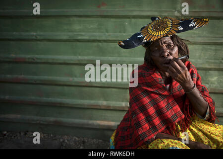 Die Herero Frau Rauch von außen ein Geschäft in Purros, Namibia. Stockfoto