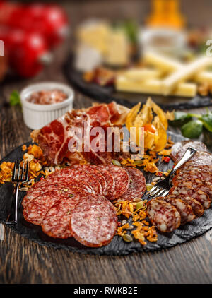 Schiefer board mit Prosciutto, Salami und Würstchen auf hölzernen Tisch Stockfoto