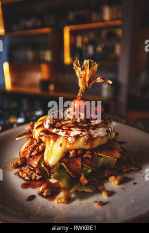 Gegrilltem Camembert mit Walnüssen und gegrillter Birne auf weiße Platte, Essen im Restaurant Stockfoto