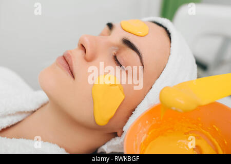Kosmetikerin, die Gesichtsmaske mit Orange auf schönen weiblichen Gesichts extrahieren Stockfoto