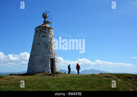 Twr Bach Rundumleuchte auf llanddwyn Island vor der Küste von Anglesey, die in den frühen 1800er Jahren gebaut wurde. Der Turm blickt auf die Berge von Snowdonia. Stockfoto