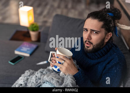 Unglückliche Mann hält eine Tasse mit Kaffee gedrückt Stockfoto