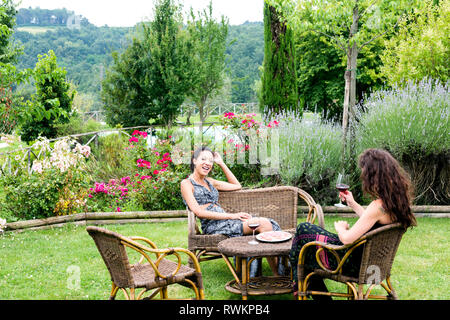 Frauen auf Korbstühlen im grünen Garten, Città della Pieve, Umbrien, Italien Stockfoto