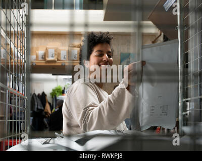 Frau mit Kuriertasche hinter Kabel Fenster Stockfoto