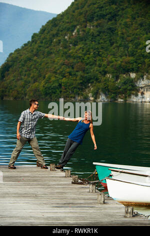 Reifes Paar balancing einander am Rande des Lac d'Annecy pier, Annecy, Rhône-Alpes, Frankreich Stockfoto