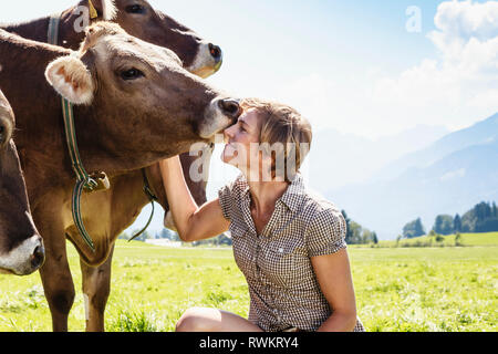 Frau Verklebung mit Kuhherde auf Feld, Sonthofen, Bayern, Deutschland Stockfoto