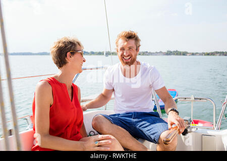 Junger Mann und reife Frau auf Segelboot auf Chiemsee, Bayern lachen, Deutschland Stockfoto