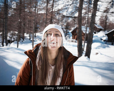 Junge Frau in Strick Hut im verschneiten Wald, Porträt, Alpe Ciamporino, Piemont, Italien Stockfoto