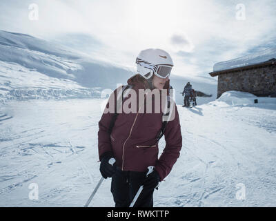 Junge weibliche Skifahrer das Tragen von Helm und Skibrille zurück in die verschneite Landschaft suchen, Alpe Ciamporino, Piemont, Italien Stockfoto