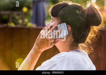 Frau mit Henna Tattoo auf der Hand mit Smartphone Stockfoto