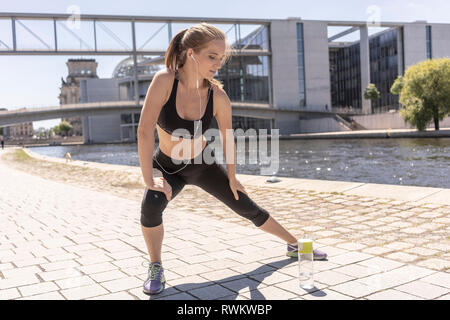 Junge Frau Stretching im City Park, Berlin, Deutschland Stockfoto